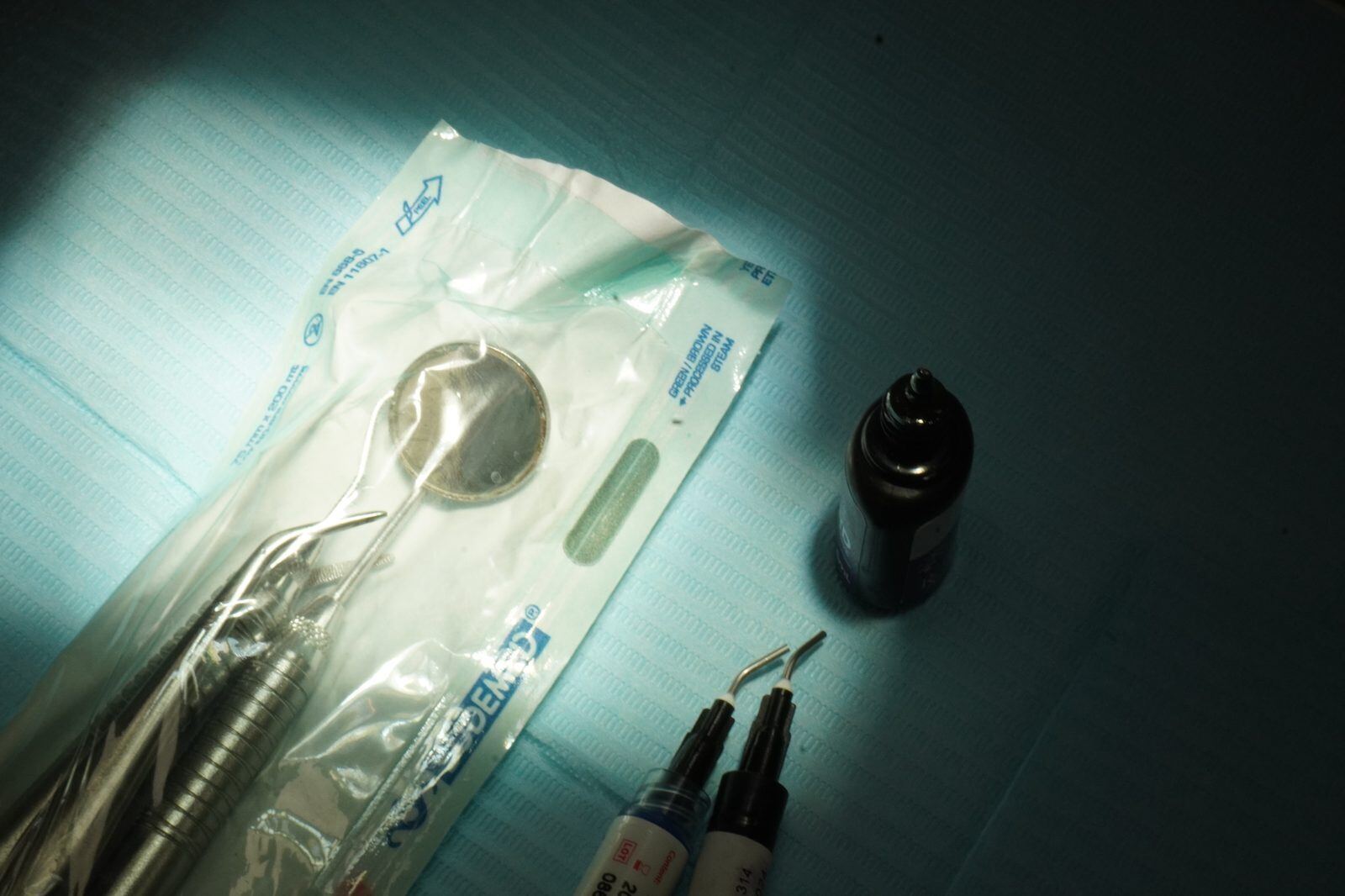 Sealed sterile instrument pouch with a steam sterilization indicator label, dental probes and mirror visible inside
